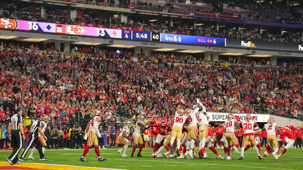 Kansas City kicker Harrison Butker kicks as the 49ers jump up to try to block it
